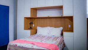 Un dormitorio con cama, cabecera de madera y escritorio con lámpara.