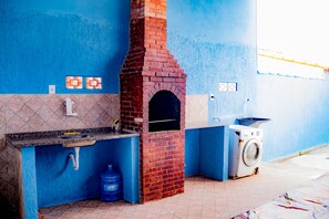 Cocina compacta con horno de ladrillo, lavadora y pared de azulejos azules.