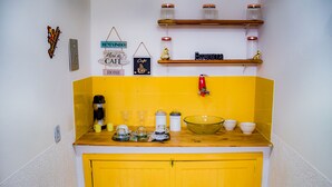 Una cocina con armarios amarillos, encimera de madera y varios utensilios de cocina como tazas, cafetera y frascos.