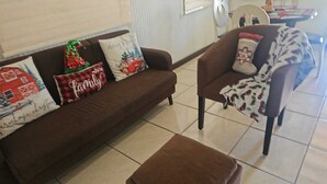 Olohuone, jossa on ruskea sohva ja nojatuoli, ja sitä koristavat juhlavat koristetyynyt.