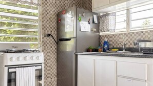 Keittiössä on Whirlpool-merkkinen liesi, ruostumattomasta teräksestä valmistettu jääkaappi ja ruutukuviollinen välitila.
