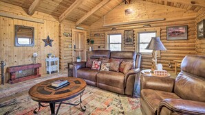 Ein rustikales Blockhaus-Interieur mit Ledersofa, Couchtisch und rustikalem Holzboden.