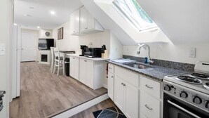 A modern kitchen with white cabinets, a granite countertop, and a skylight.
