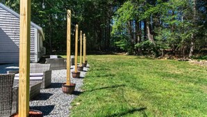 A grassy outdoor area with a row of wooden posts and wicker furniture.