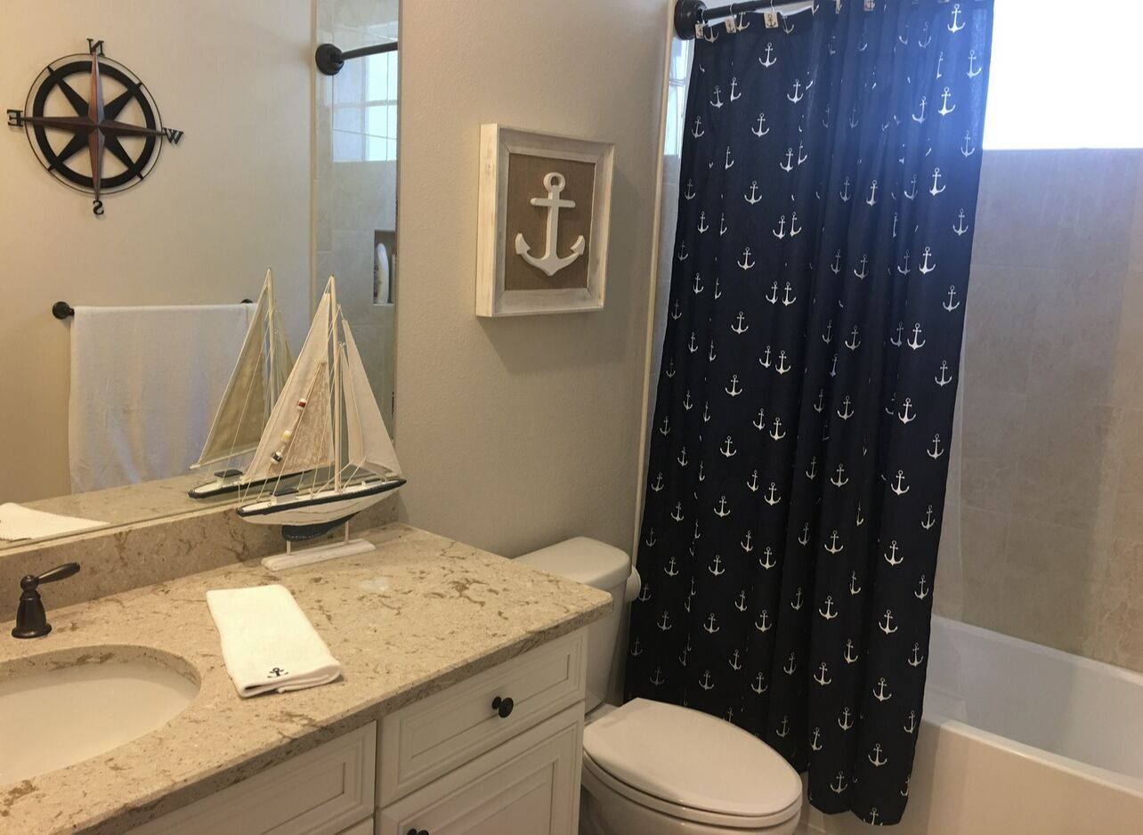 Un bagno con lavandino, specchio e un modellino di barca a vela.
