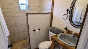 Ein Badezimmer mit Dusche, Toilette, Waschbecken und Fenster.