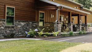 A modern building with a stone facade, wooden exterior, and a covered porch with outdoor seating. - Wildflower Paradise: Luxury Lodge Suite in Amish Country (Dundee)