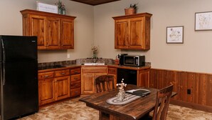 A kitchen with wooden cabinets, a refrigerator, a microwave, and a dining table with chairs. - Wildflower Paradise: Luxury Lodge Suite in Amish Country (Dundee)