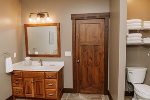 Une salle de bain avec un meuble-lavabo en bois, un grand miroir et des toilettes.