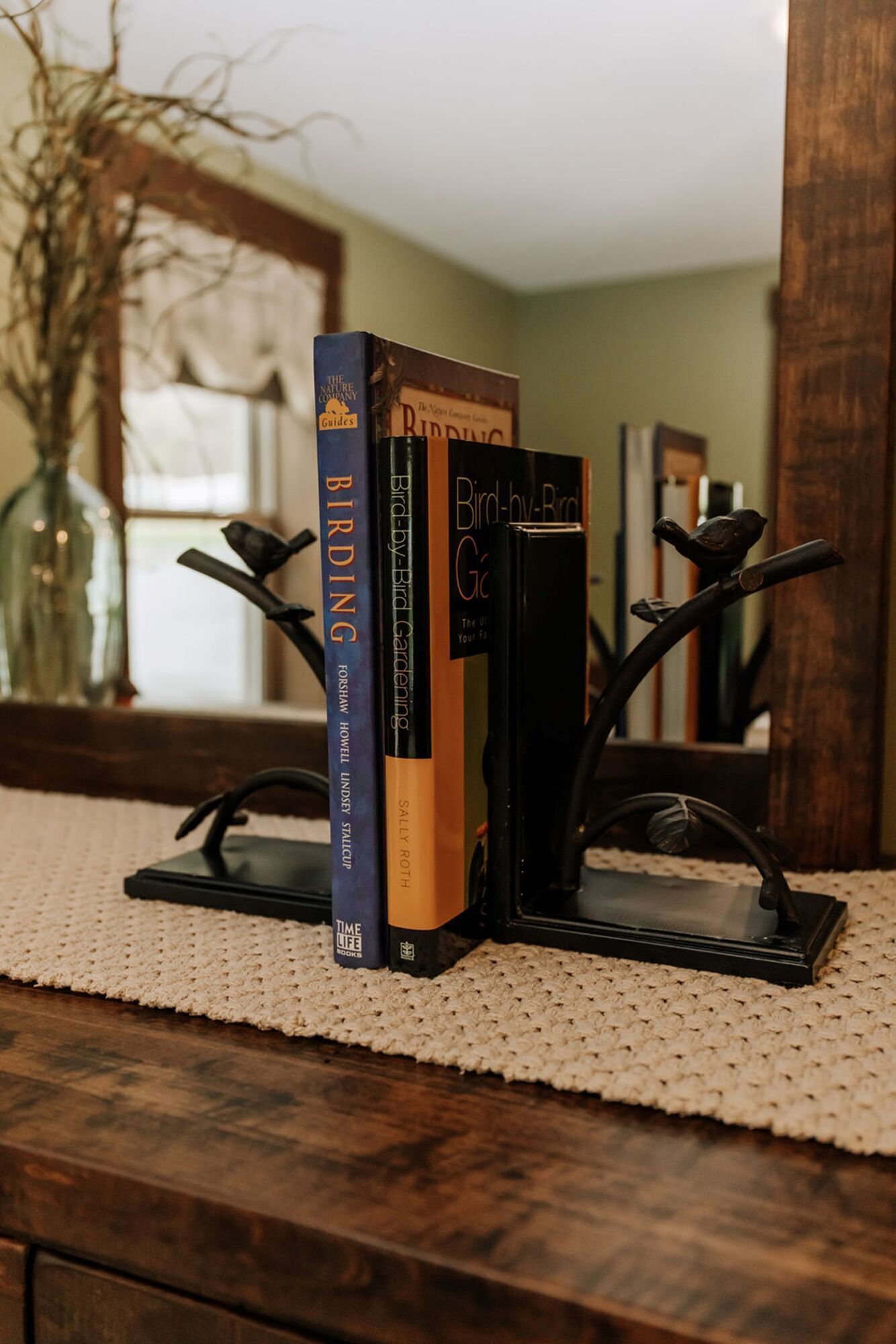 A stack of books on a wooden stand with a woven placemat underneath.