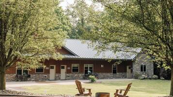 Eine Lodge mit Steinverkleidung, einem Metalldach und einer Terrasse mit Adirondack-Stühlen.