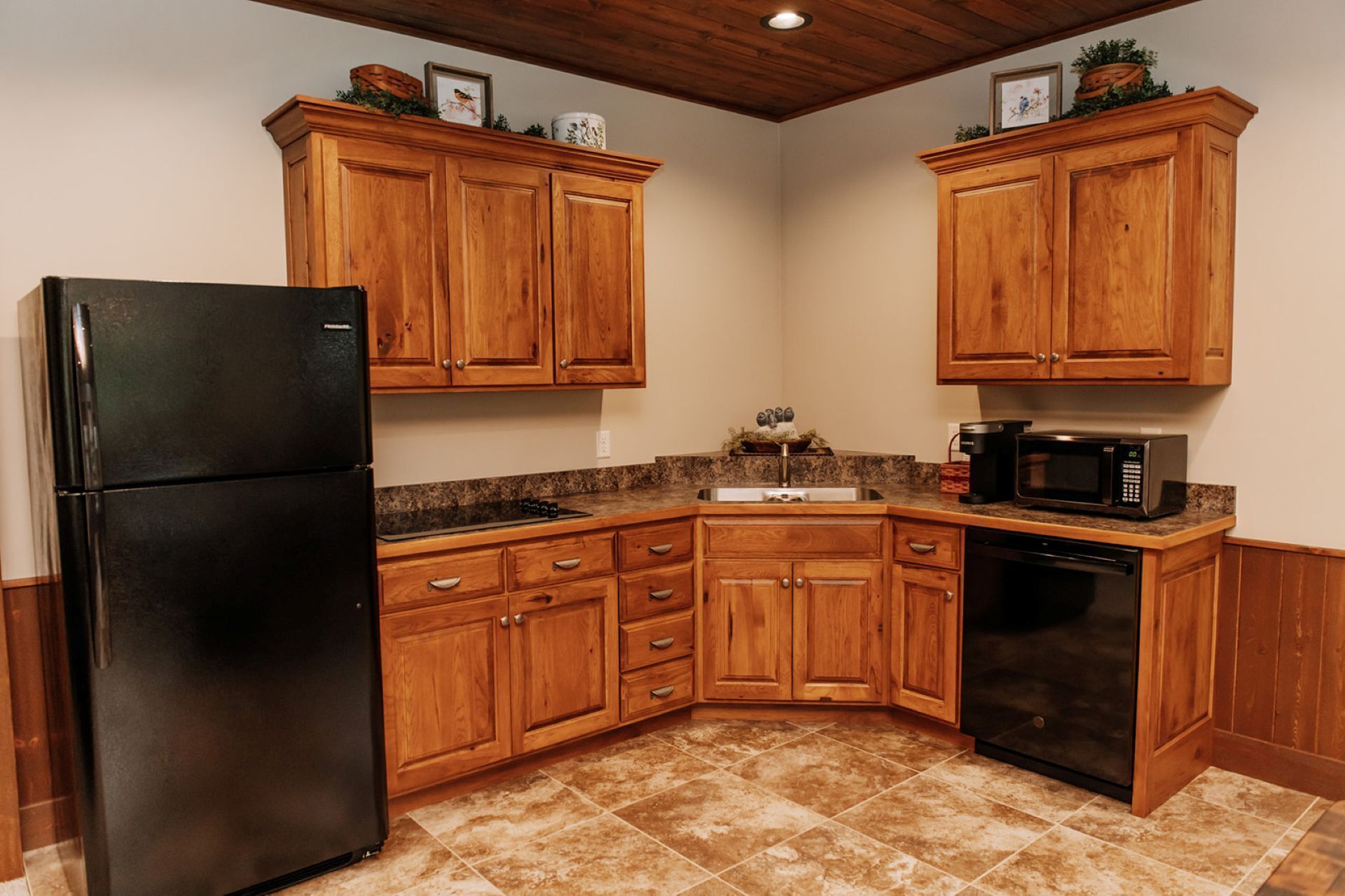 A kitchen with wooden cabinets, a black refrigerator, a microwave, and a dishwasher.