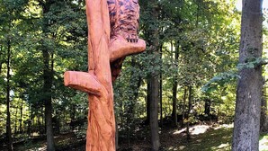 Eine Holzskulptur von Eulen in einer Waldlandschaft.