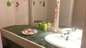 A bathroom with a sink, mirror, and green soap dispensers. - Large secure studio, 50 meters from Bas du Fort beach. (Le Gosier)