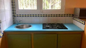 A kitchen with a blue countertop, a gas stove, a sink, and a window with decorative glass. - Large secure studio, 50 meters from Bas du Fort beach. (Le Gosier)