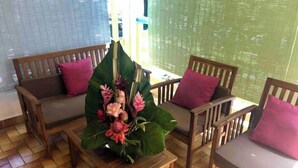 A room with wooden furniture, including two sofas and a small table, with a large green plant centerpiece. - Large secure studio, 50 meters from Bas du Fort beach. (Le Gosier)