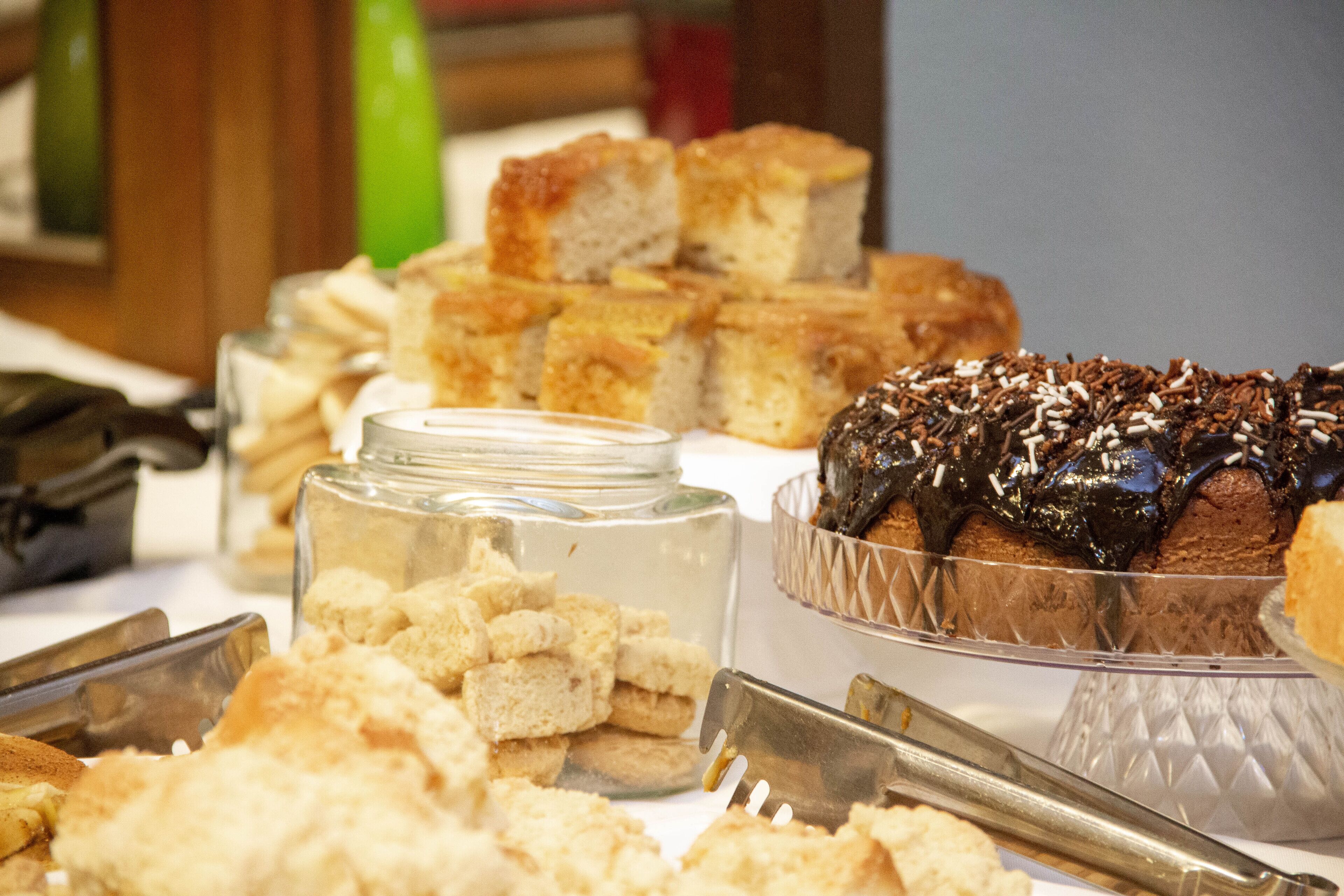 Un bufé con diversos alimentos, incluyendo pan, pasteles y un postre de chocolate.