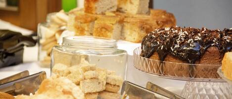 A buffet with various food items including bread, cakes, and a chocolate dessert.