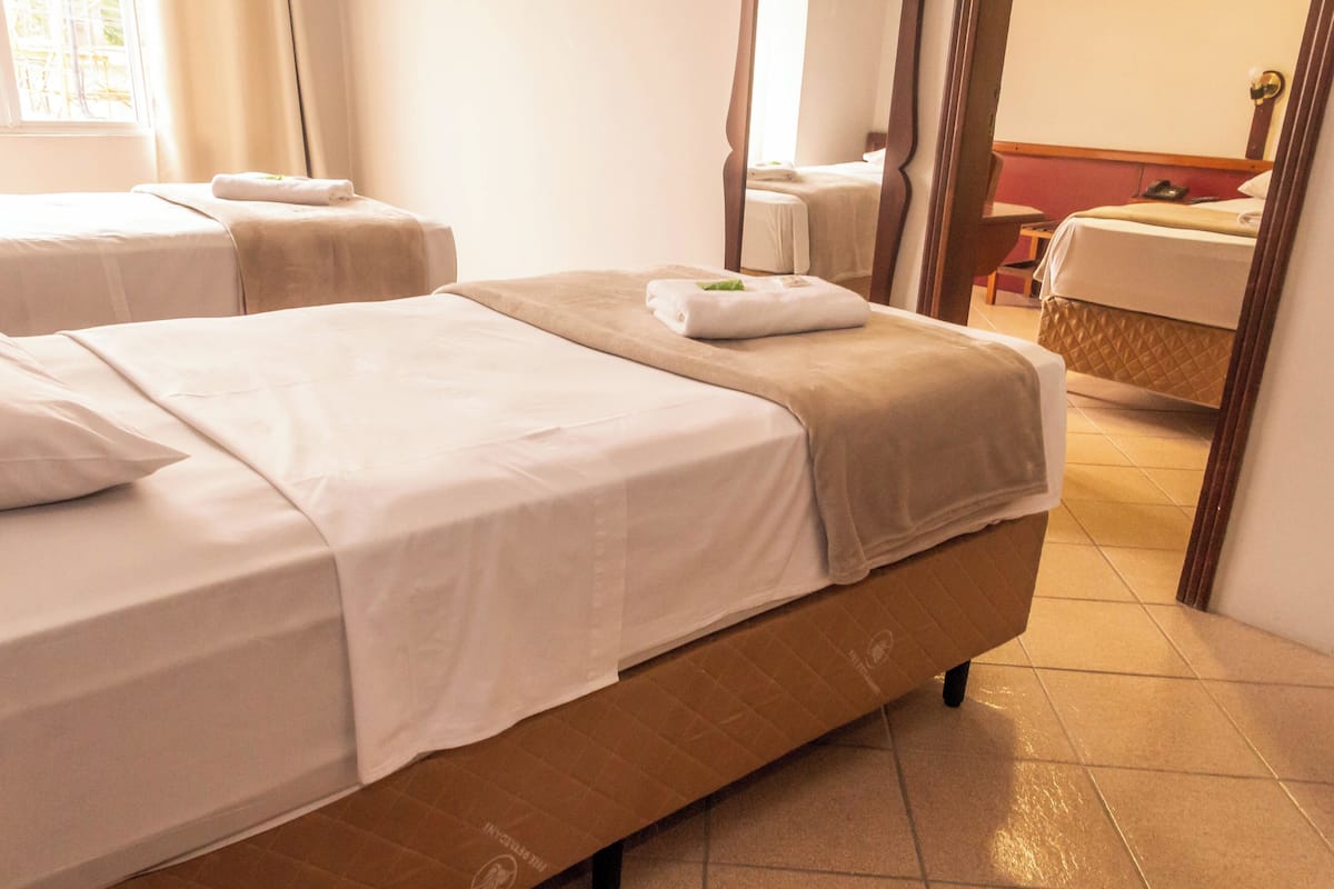 A hotel room with two beds, a bathroom, and a mirror.