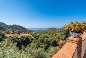 Eine Terrasse mit Blick auf eine hügelige Landschaft und das Meer.