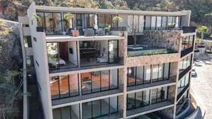 A modern multi-story building with balconies, large windows, and a curved design. - CONDO P1 BY TRVL2HM (Cabo San Lucas)