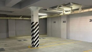 A parking garage with concrete pillars, yellow parking lines, and numbers 303 on the walls. - CONDO P1 BY TRVL2HM (Cabo San Lucas)