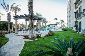 Une cour d’hôtel avec une piscine, des palmiers et des espaces de détente en plein air.
