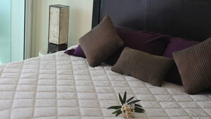A neatly made bed with a quilted white duvet, two striped pillows, and a small floral arrangement on the bed. - Condo PC by TRVL2HM (Cabo San Lucas)