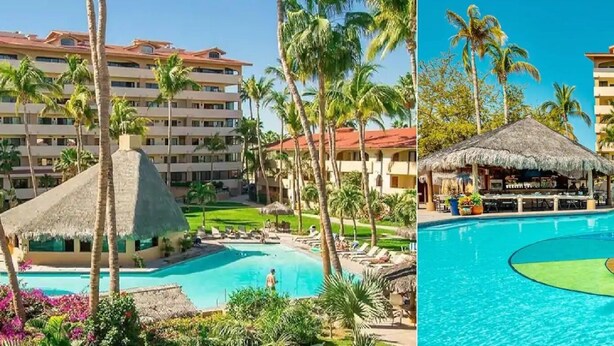 Un resort con varias edificaciones, una piscina y estructuras de techo de paja.
