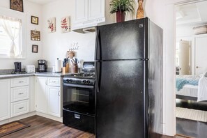 Una cuina amb armaris blancs, un refrigerador negre, una cuina i una cafetera.