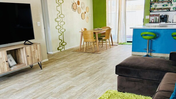A modern living room with a flat-screen TV, wooden furniture, and a green rug. - Casa Arizu, w/ rv parking and private pool (Lake Havasu City)
