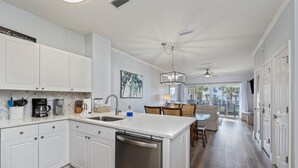 Uma cozinha moderna com armários brancos, lava-louças embutida e um espaço de refeições com vista.