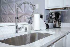 Enjoy cooking in this well-equipped kitchen with a stainless steel sink, faucet, and coffee maker.