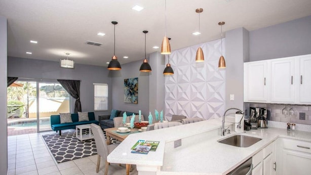 A modern kitchen with white cabinets, a central island, and pendant lighting.