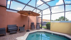 An indoor swimming pool with a glass ceiling, lounge chairs, and an umbrella.