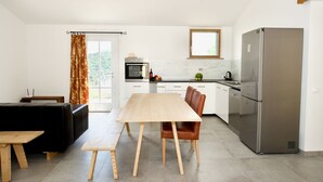 Eine moderne Küche mit einem Holzespeisetisch, einer schwarzen Couch und einem Edelstahlkühlschrank.