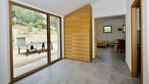 Ein modernes Interieur mit einer Schiebetür zum Außenbereich, einem Holzschrank und einem kleinen Tisch mit Stuhl.