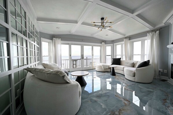 Relax in this spacious living room with a high ceiling and stunning sea views.