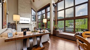 Amplia sala de estar con chimenea, ventanas grandes y vistas al exterior.