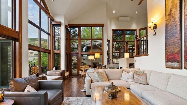 Un amplio salón con ventanas grandes, una mesa de centro de madera y un sofá.