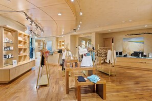 Een ruime fitnessclub met houten vloeren, kledingrekken en een receptiebalie.