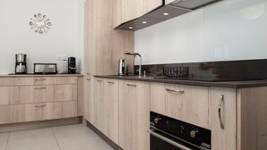 Ett modernt kök med ljusa träskåp, en rostfri köksfläkt och en inbyggd ugn.