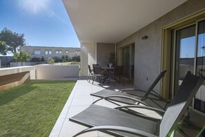 Un balcó amb taula i cadires, una zona verda i un edifici al fons.