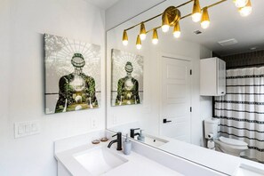 Ein modernes Badezimmer mit einem großen Spiegel, zwei Waschbecken, einer Toilette und einer Duschkabine.