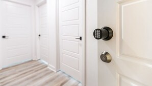 A hallway with white doors, a modern keypad lock, and a traditional key lock. - EastSide Austin · Quaint 4 Bedroom Eastside Lodge (Pet Friendly & Work Space) (Austin)