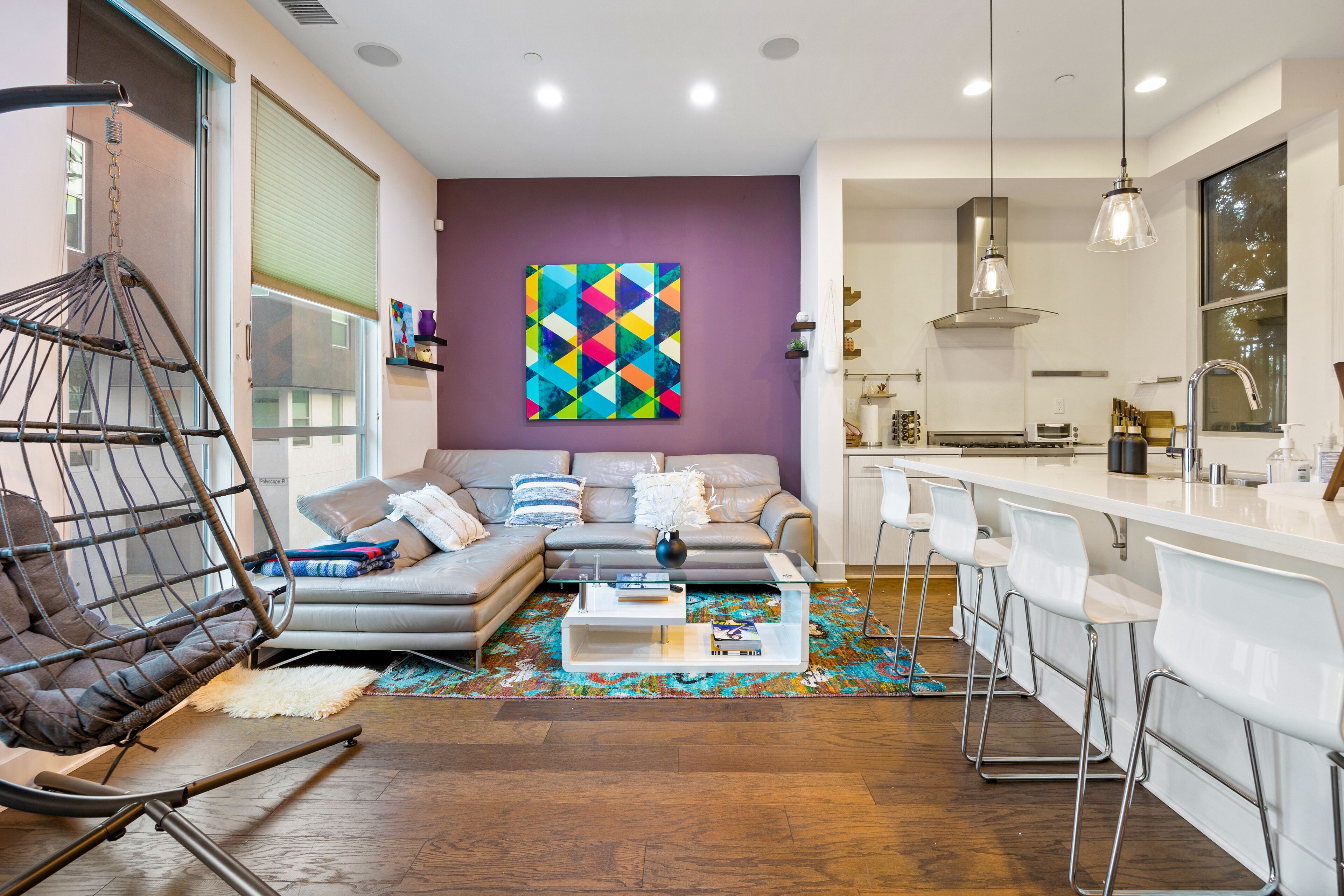 A modern living room with a sofa, a hanging chair, a coffee table, and a colorful abstract painting on the wall. - ★Insta-Worthy Sunset View ★Private Rooftop ★Garage ★Silver Lake ★Dodgers Stadium (Los Angeles)