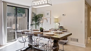 Comedor con mesa de vidrio, sillas transparentes y una araña.