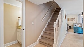 Una escalera con paredes color beige y una alfombra de tonos claros.
