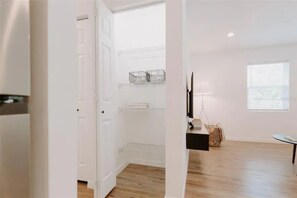 Ein geräumiges Zimmer mit Holzboden, einer weißen Tür, einem kleinen Tisch und einem Fenster.
