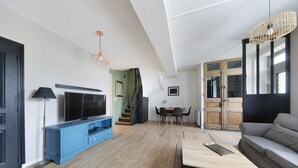 Ett modernt vardagsrum med en tv, en blå tv-bänk och en grå soffa.